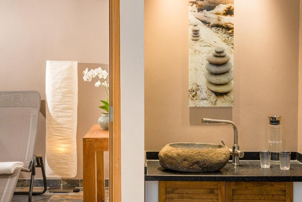 A bathroom with a stone sink, a towel rack, and a wall-mounted picture of stones.