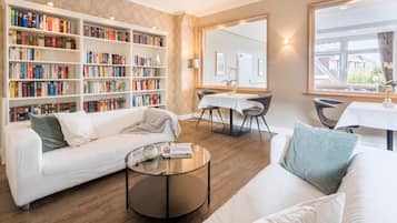 Een moderne woonkamer met een witte bank, een bijzettafeltje en een boekenplank vol boeken.