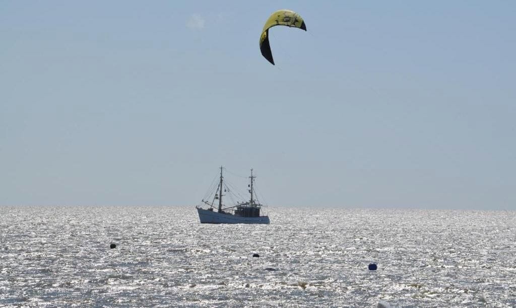 A large body of water with a ship and a parasail in the distance.
