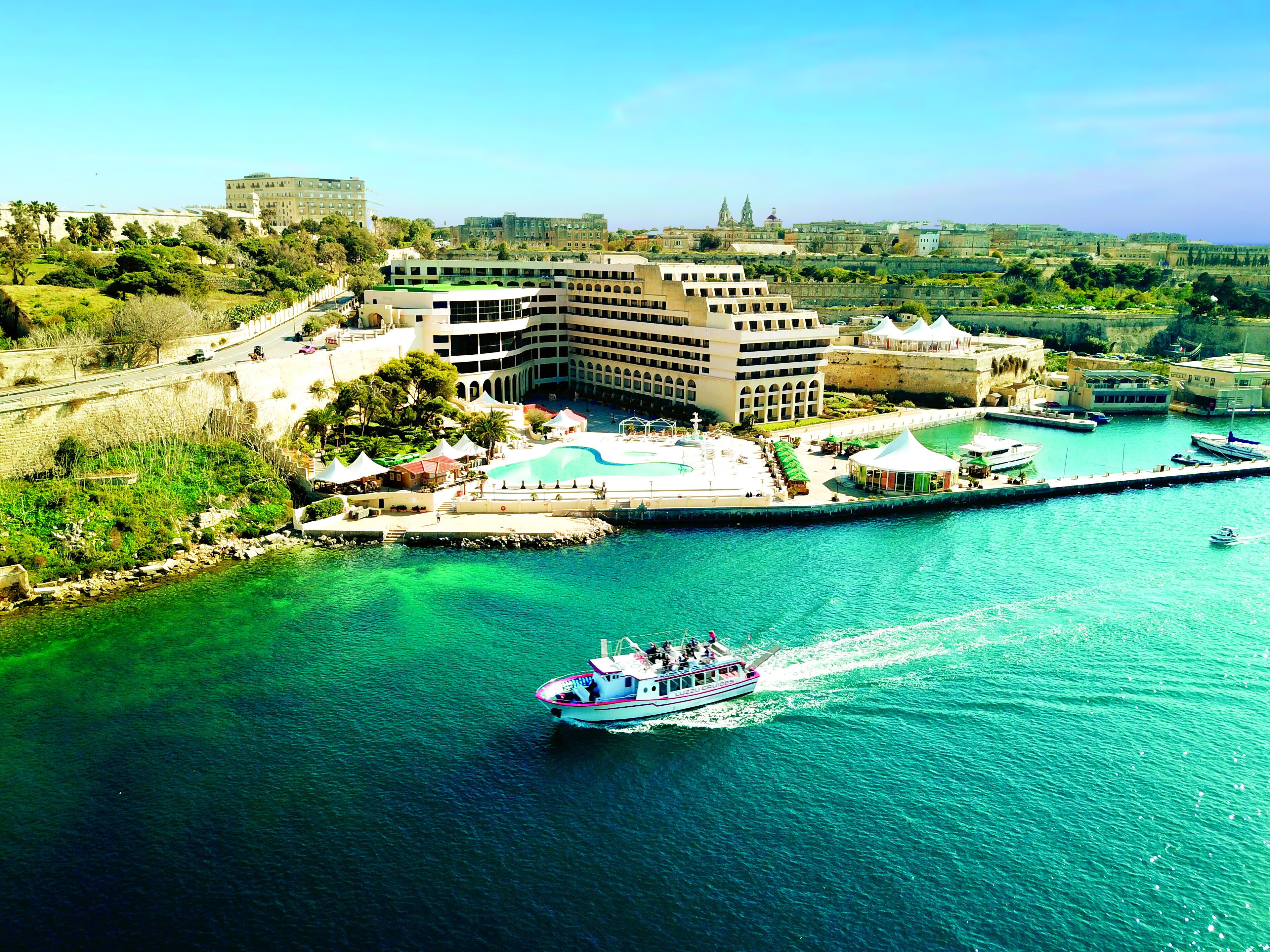 Un hôtel situé sur la côte, doté d’une piscine, d’un port de plaisance et offrant une vue sur le paysage urbain.