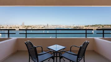 Un balcón con dos sillas y una mesa, con vista a la ciudad y al mar.