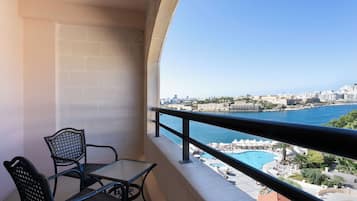 Ein Balkon mit Tisch und Stühlen mit Blick auf eine Küstenstadt, inklusive Schwimmbad und Strand.