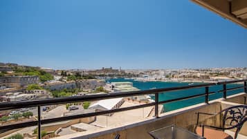 A balcony with a view of a coastal cityscape, including buildings and a marina.