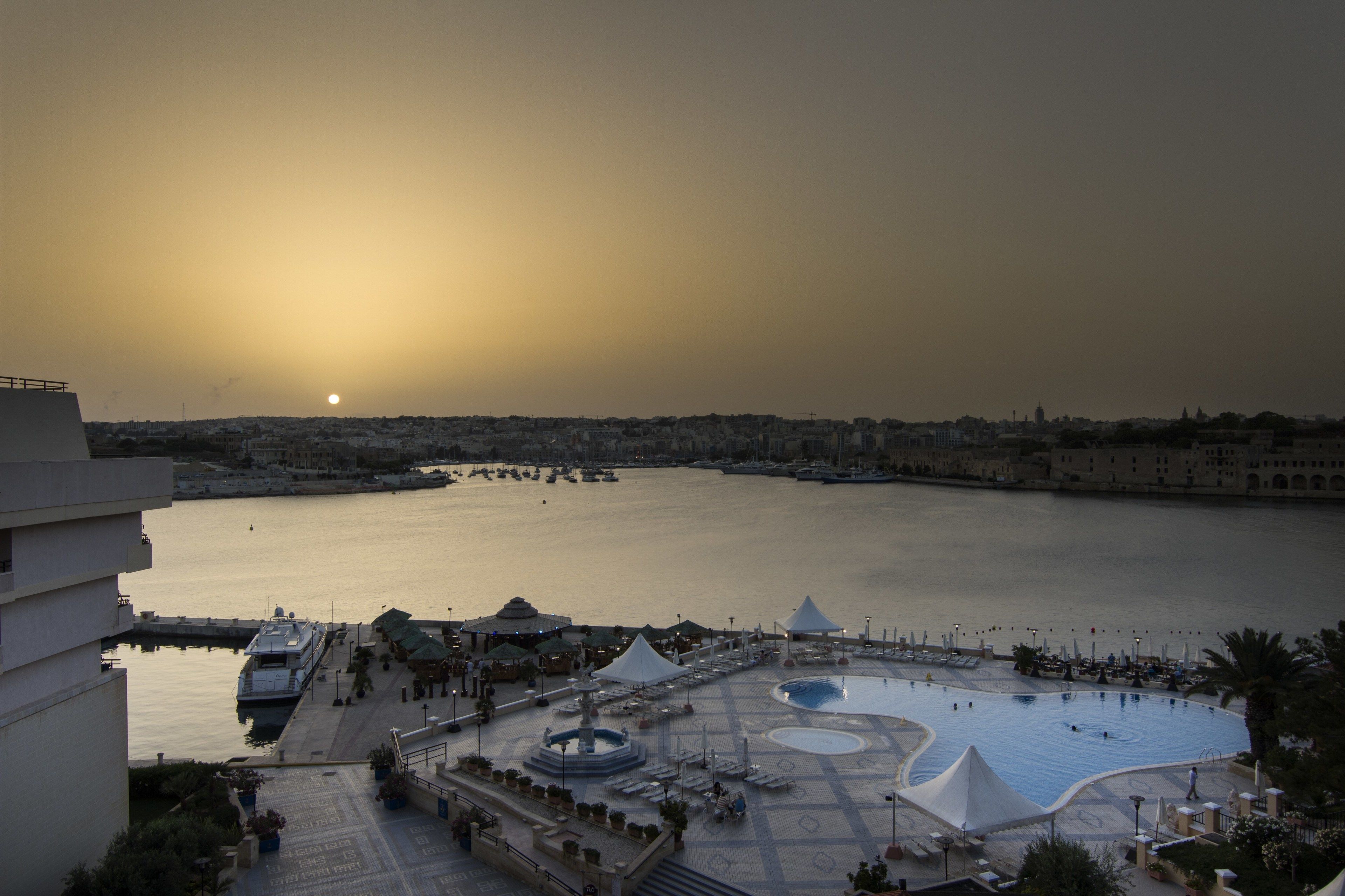 A waterfront hotel with a pool, outdoor seating, and a view of the sea.