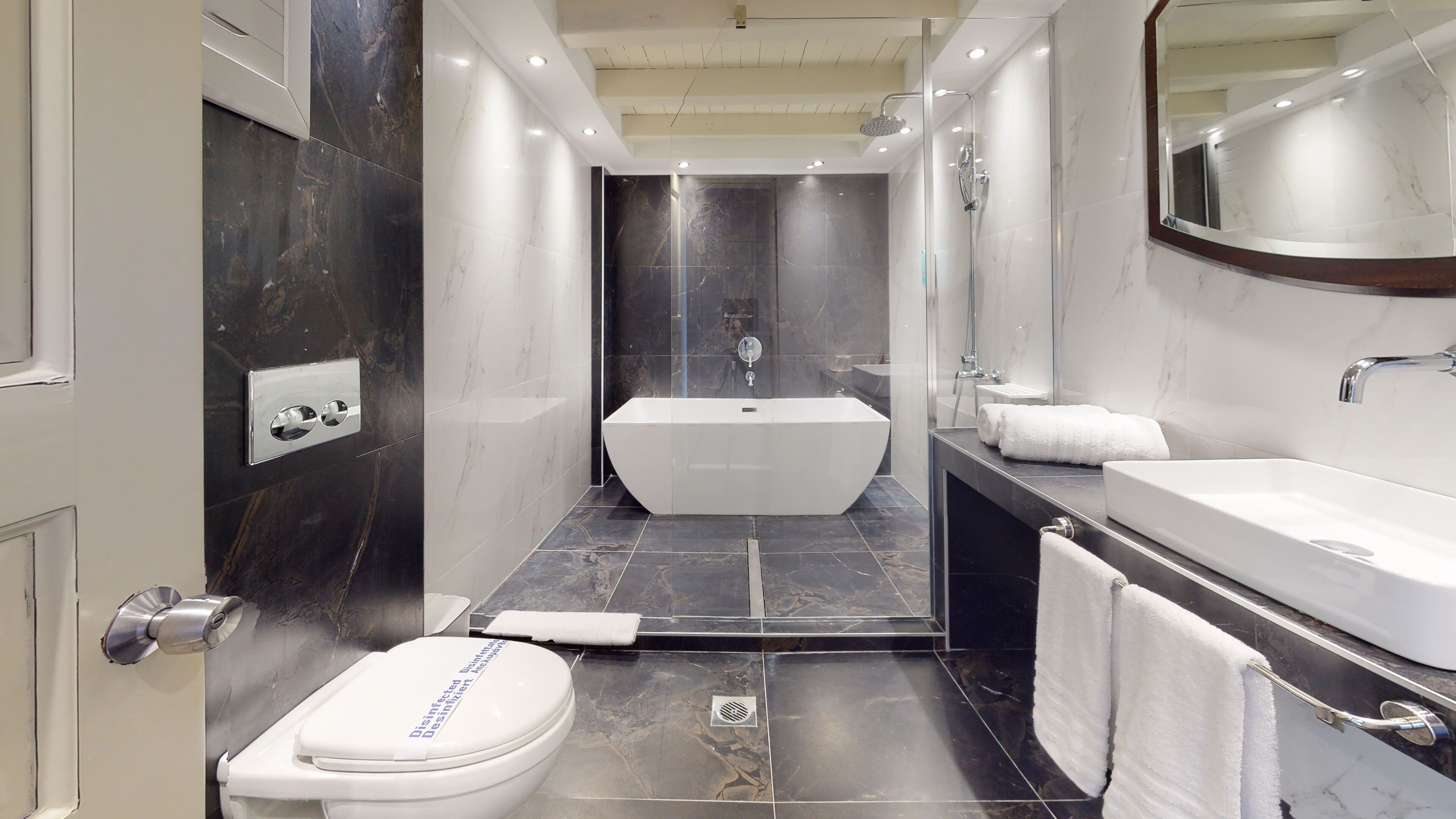 A modern bathroom with a bathtub, toilet, and vanity.