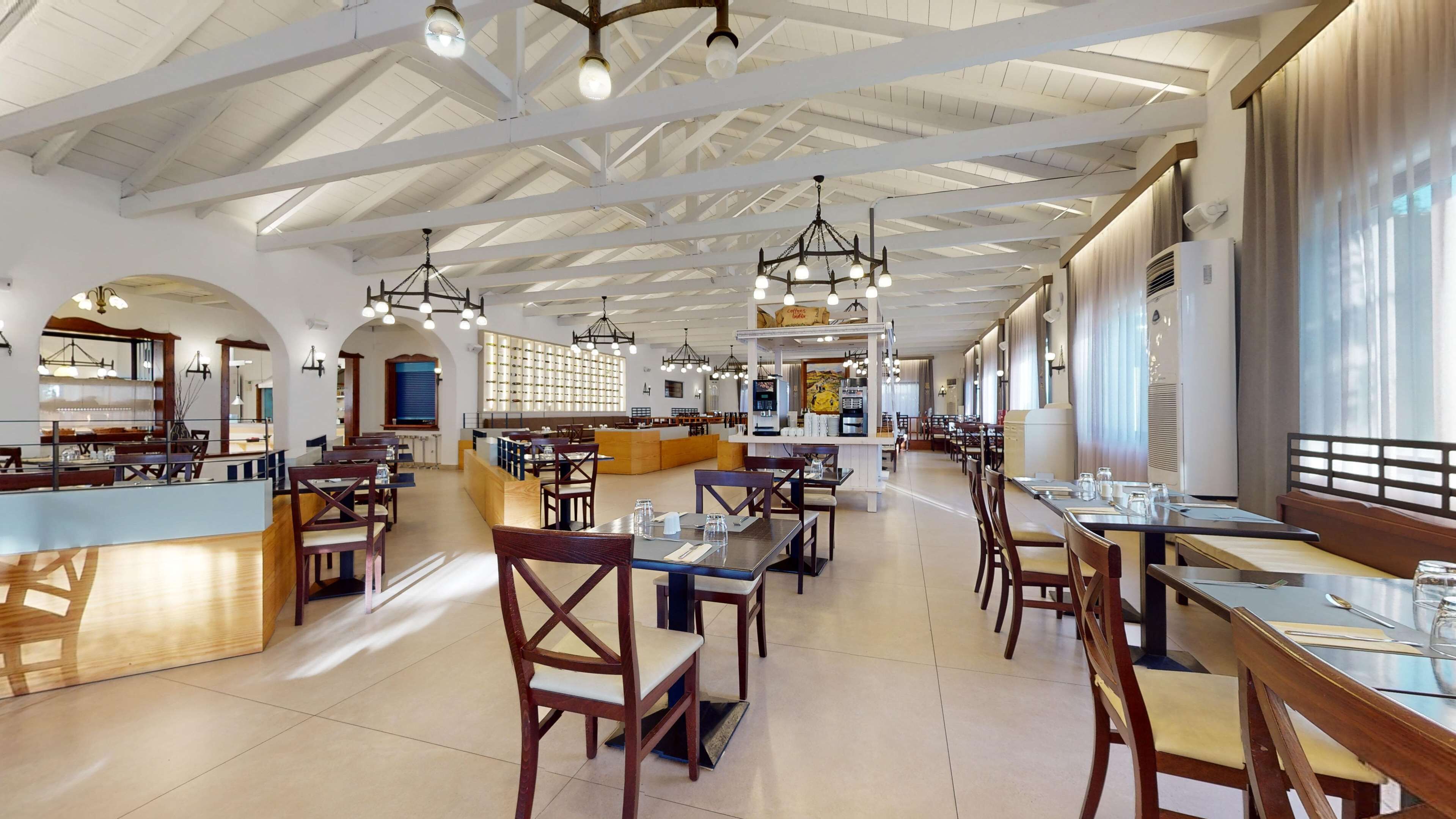 A spacious restaurant with high ceilings, multiple dining areas, and a variety of seating options including tables and booths.