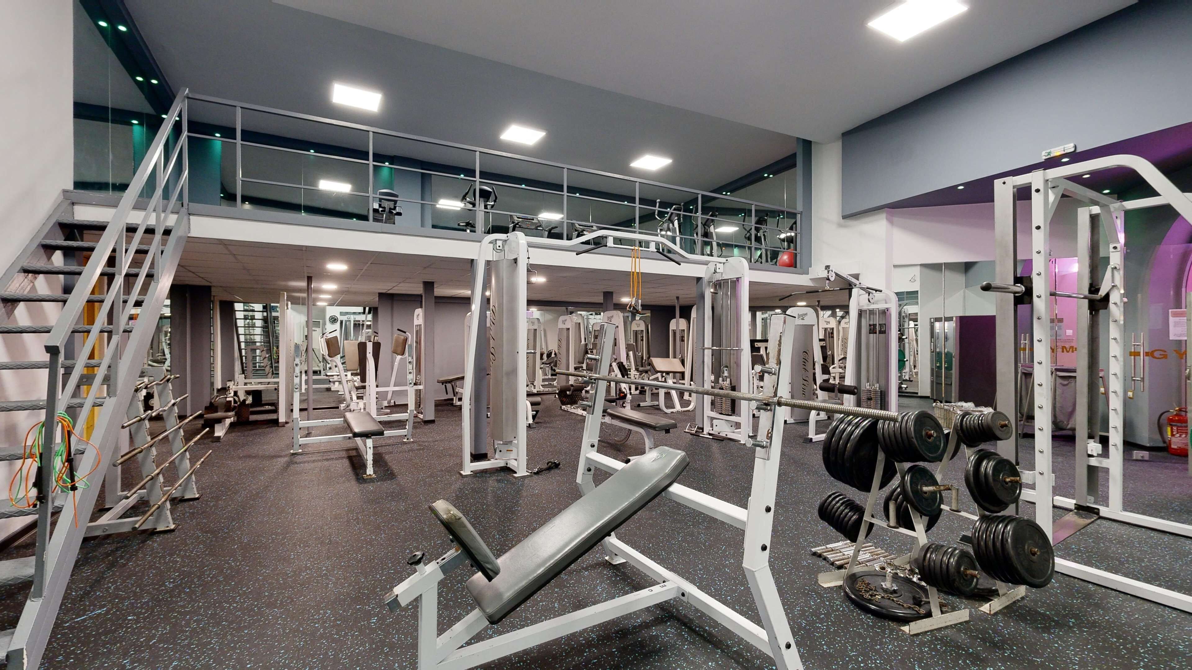 Un gimnasio con equipos de ejercicio variados, incluyendo máquinas de pesas y pesas libres.