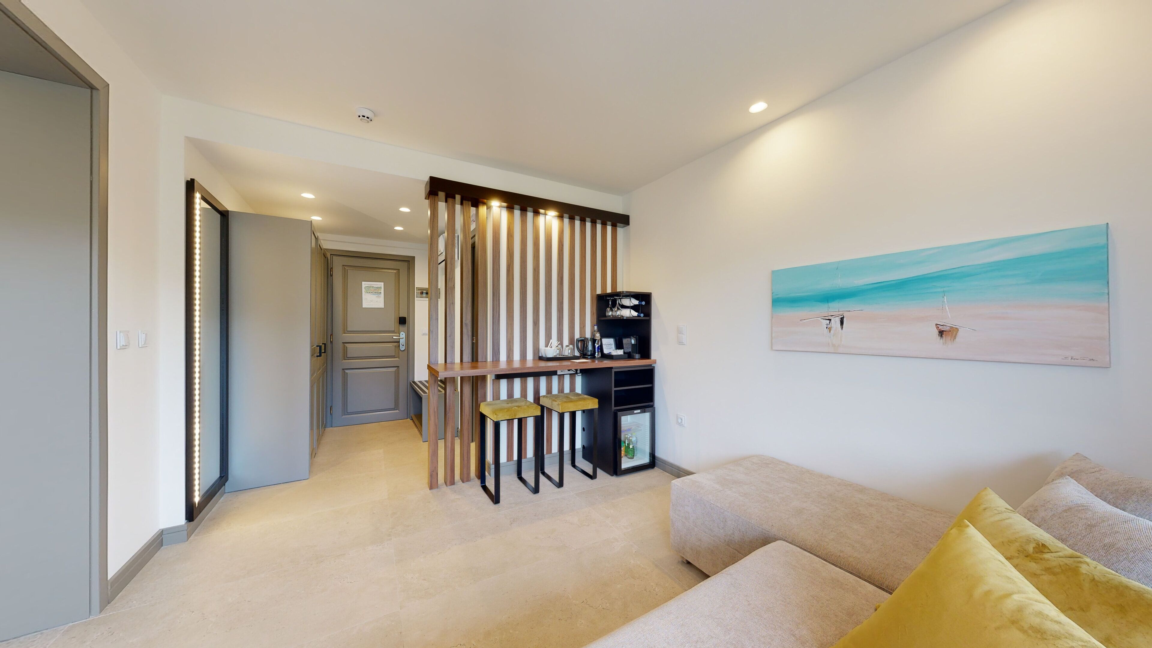 A modern living room with a sofa, a coffee table, and a painting of a beach scene.