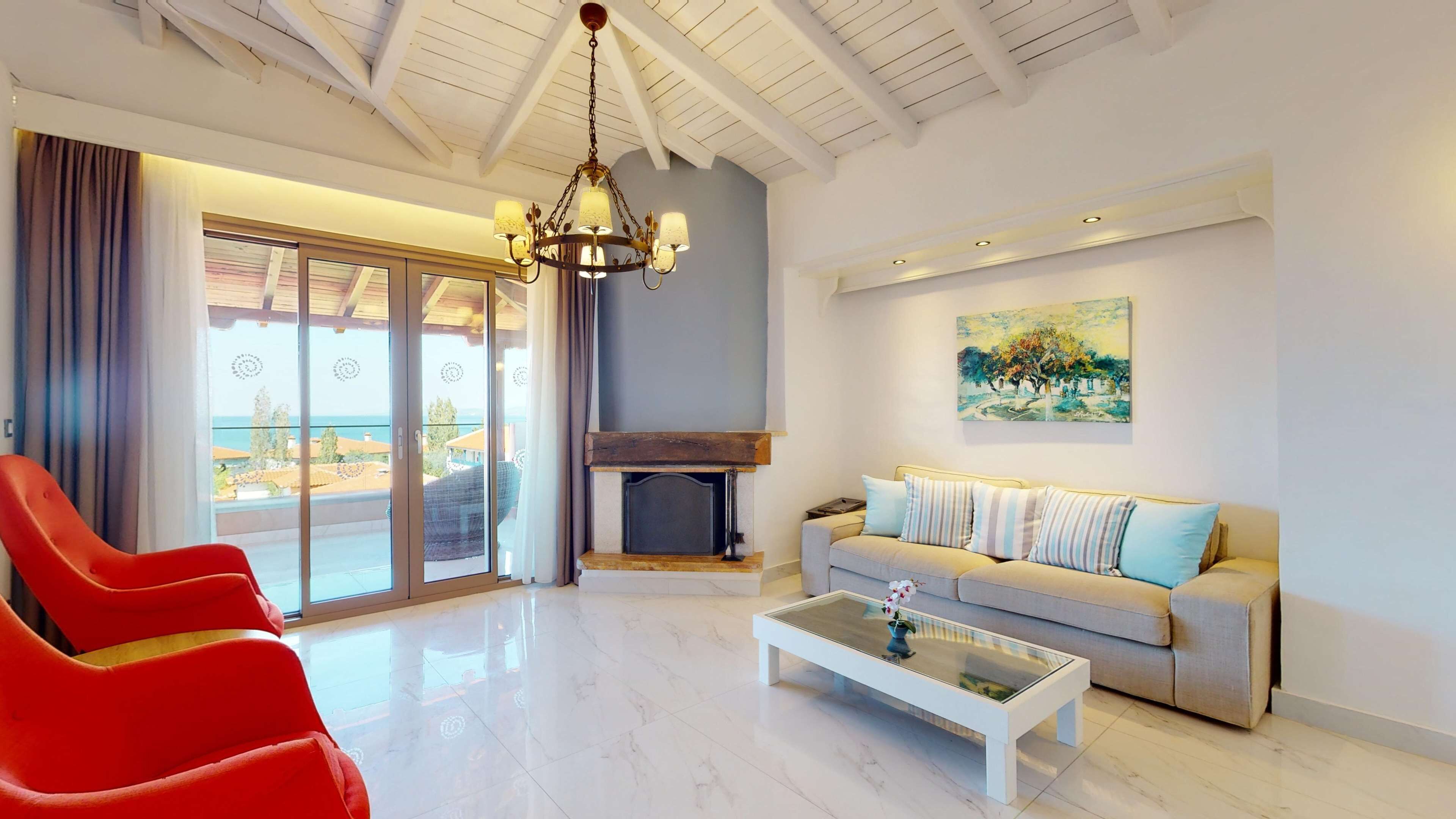 A spacious living room with a modern fireplace, a sofa set, a red chair, and a glass coffee table.