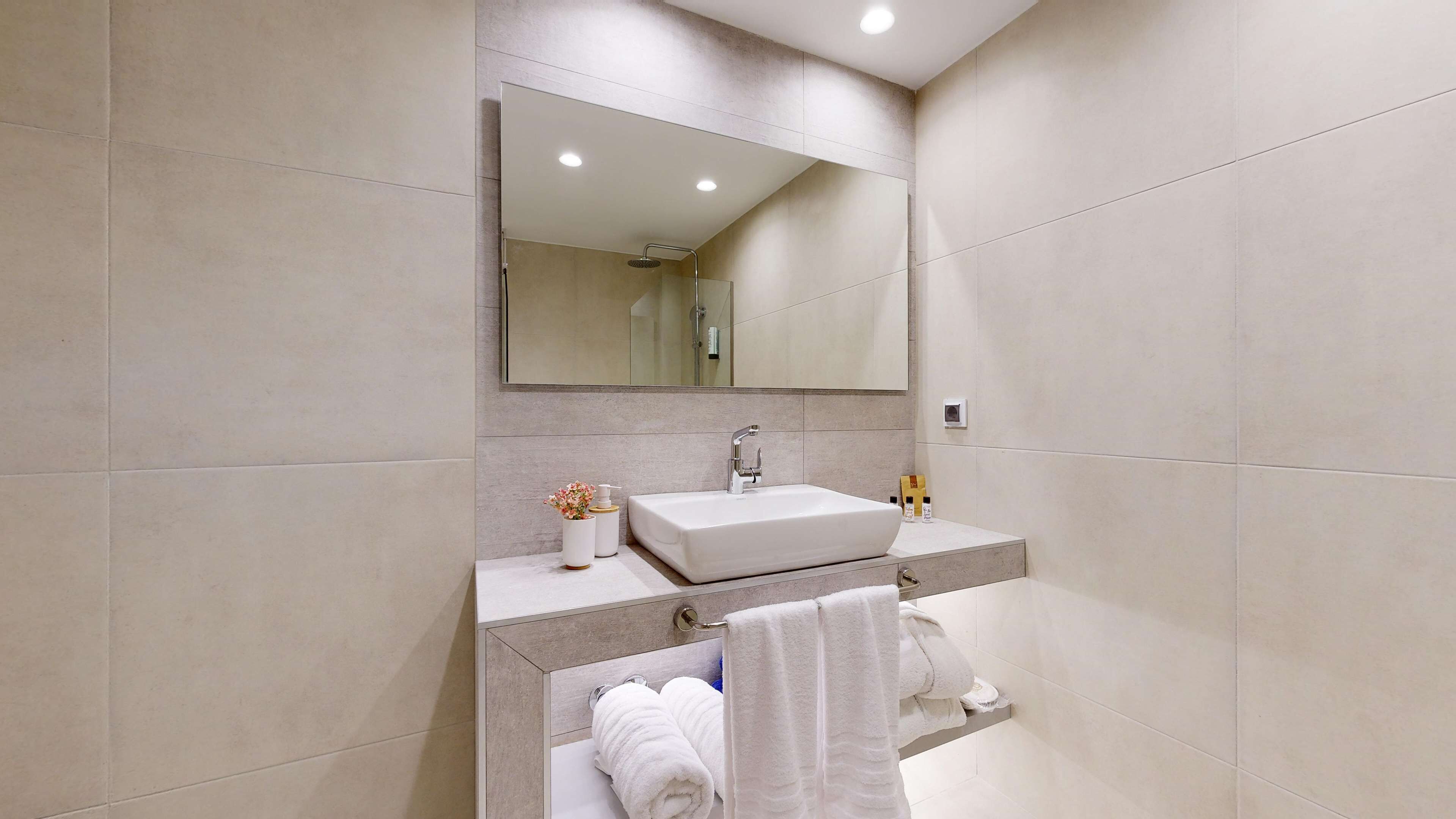 A modern bathroom with a large mirror, a sink, and a towel rack.