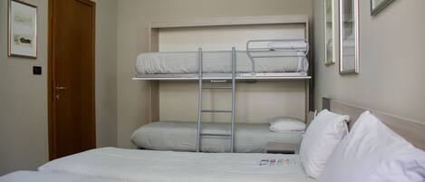 A room with a bunk bed, a wooden door, and a framed picture on the wall.
