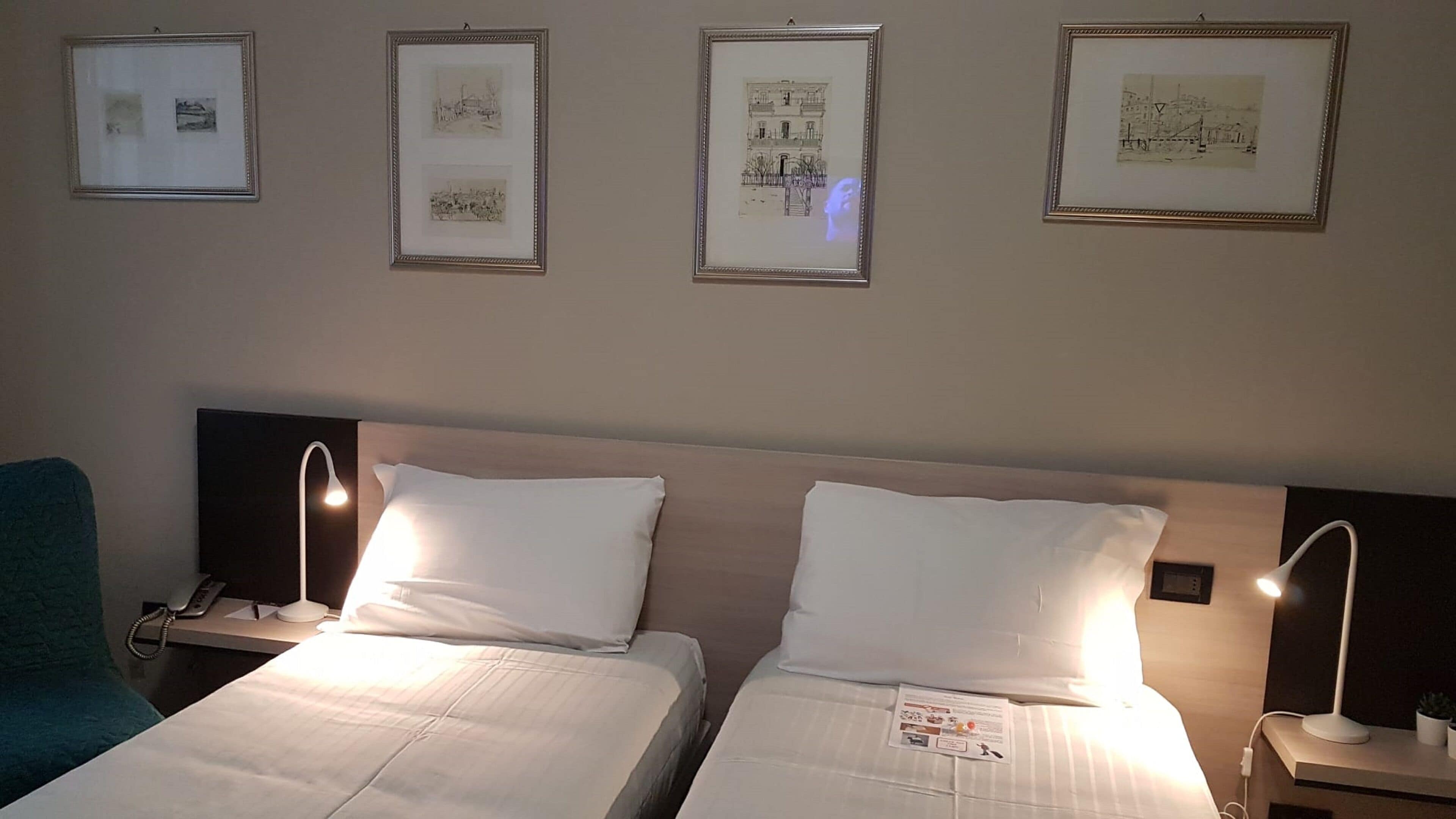 Ett hotellrum med två sängar, ett skrivbord, en telefon och inramade tavlor på väggen.