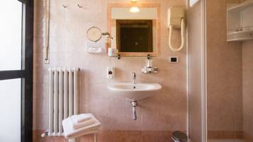 Un bagno con lavandino, specchio, porta asciugamani e water.