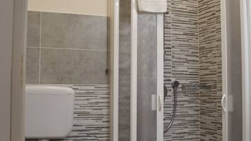 Un baño moderno con cabina de ducha, inodoro y lavamanos.