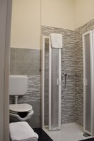 Un baño moderno con cabina de ducha, inodoro y lavamanos.