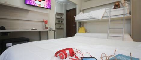 A hotel room with a bed, a desk, a TV, and a bunk bed.