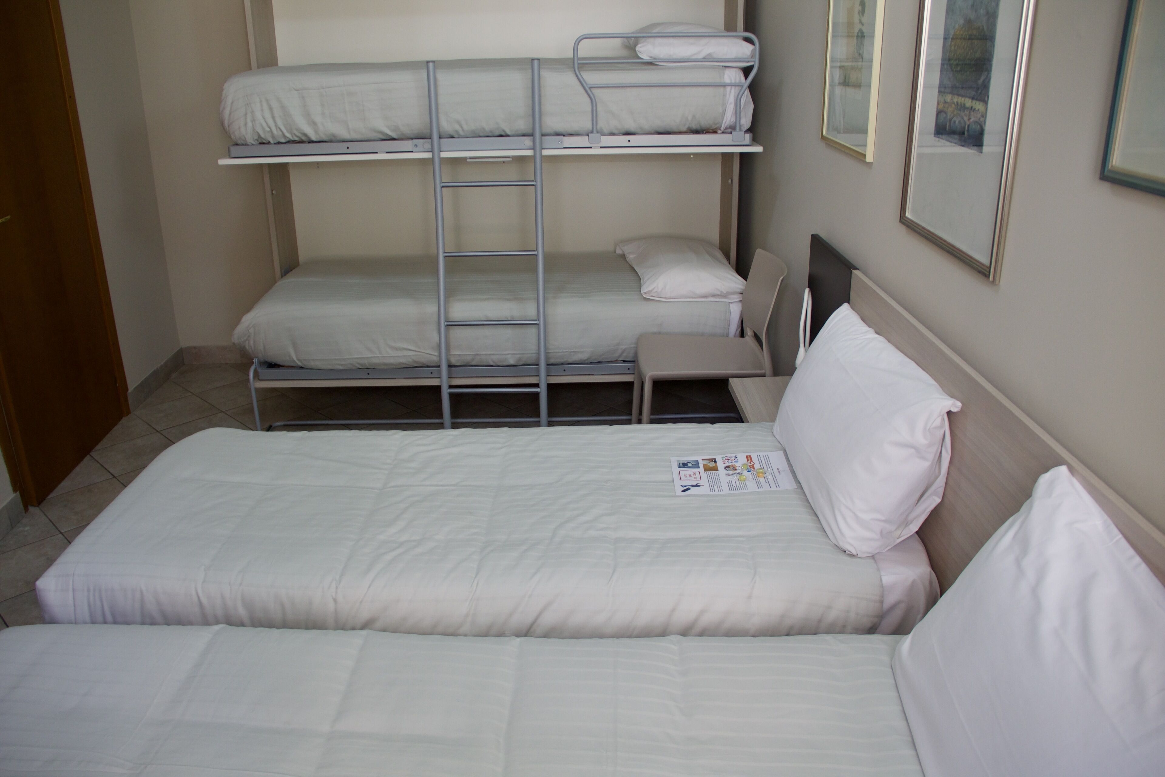 A bunk bed room with a ladder, a single bed, and a chair.