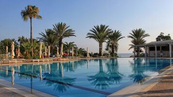 Relax by the pool surrounded by palm trees and lounge chairs.