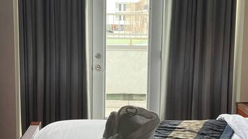 A hotel room with a bed, a set of towels, and a view through a door.