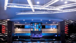 A modern bar area with a central bar counter, multiple seating options, and a decorative ceiling light fixture.