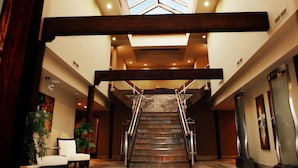 A grand staircase with metal railings, leading to a high ceiling with skylights.