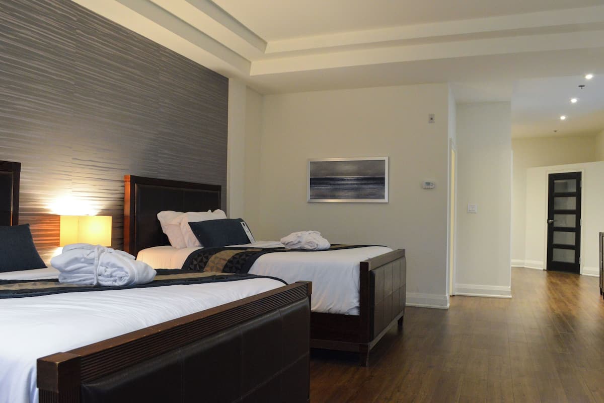 A hotel room with two beds, a large window, and a door leading to another room.