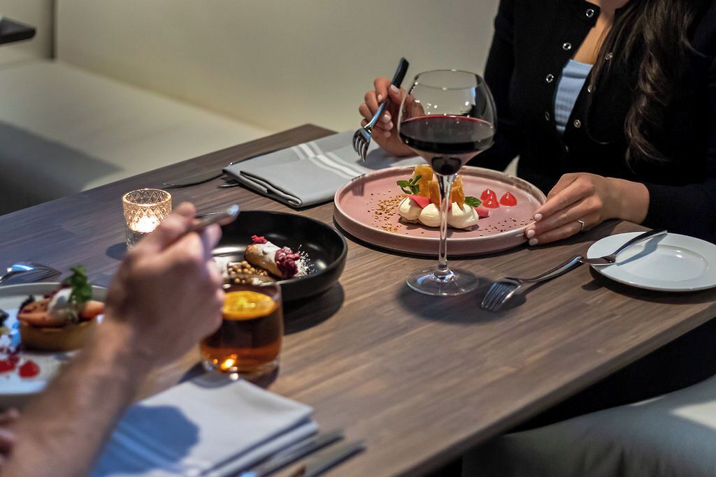 Uma mesa de jantar com um prato de sobremesa, uma taça de vinho e uma vela.