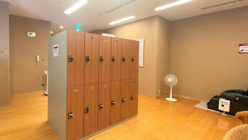 A hotel room with wooden lockers, a scale, a fan, and a charging station.