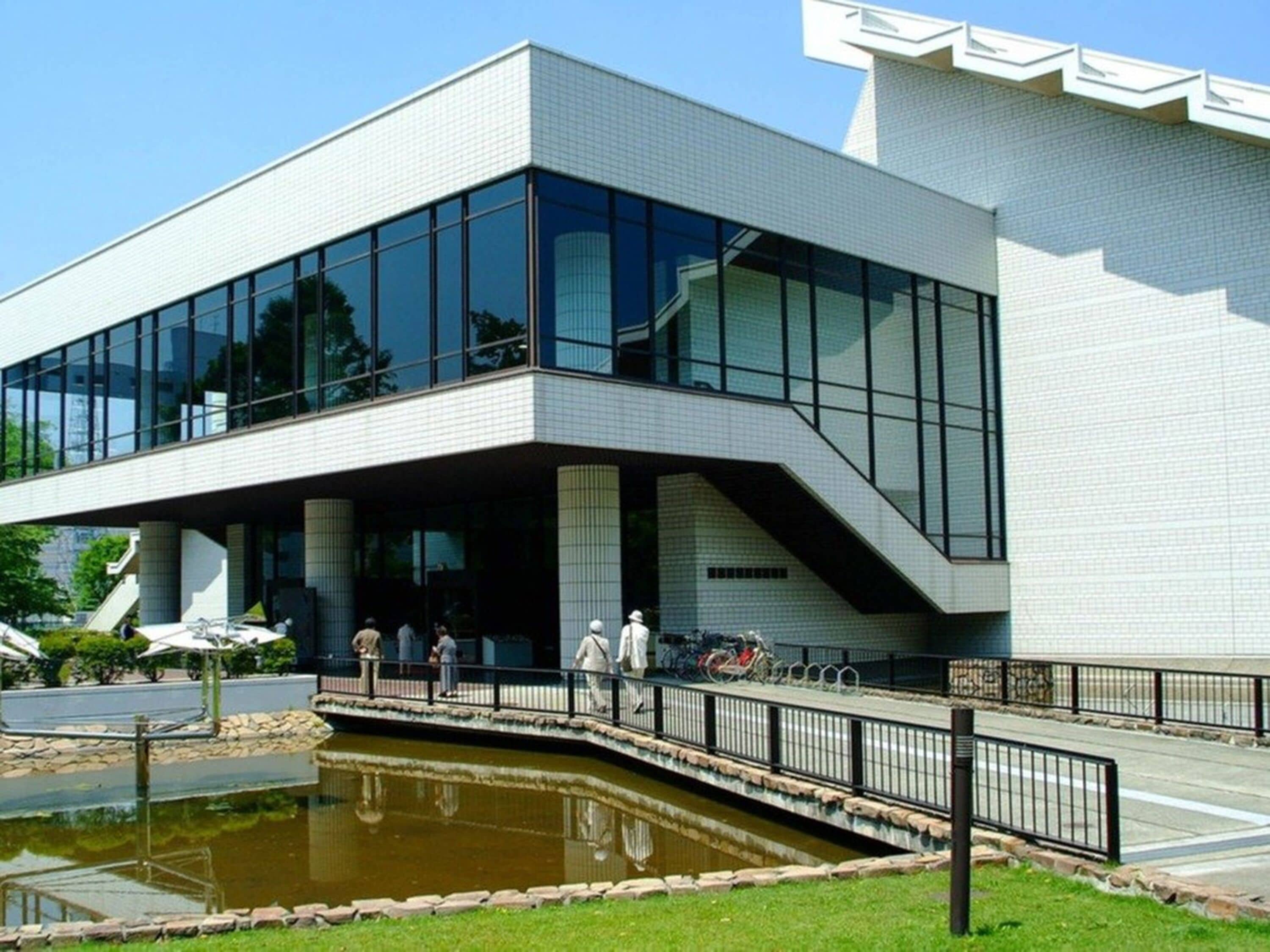A modern building with large glass windows and a covered entrance area.