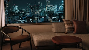 Un salon moderne offrant une vue sur le paysage urbain illuminé la nuit.