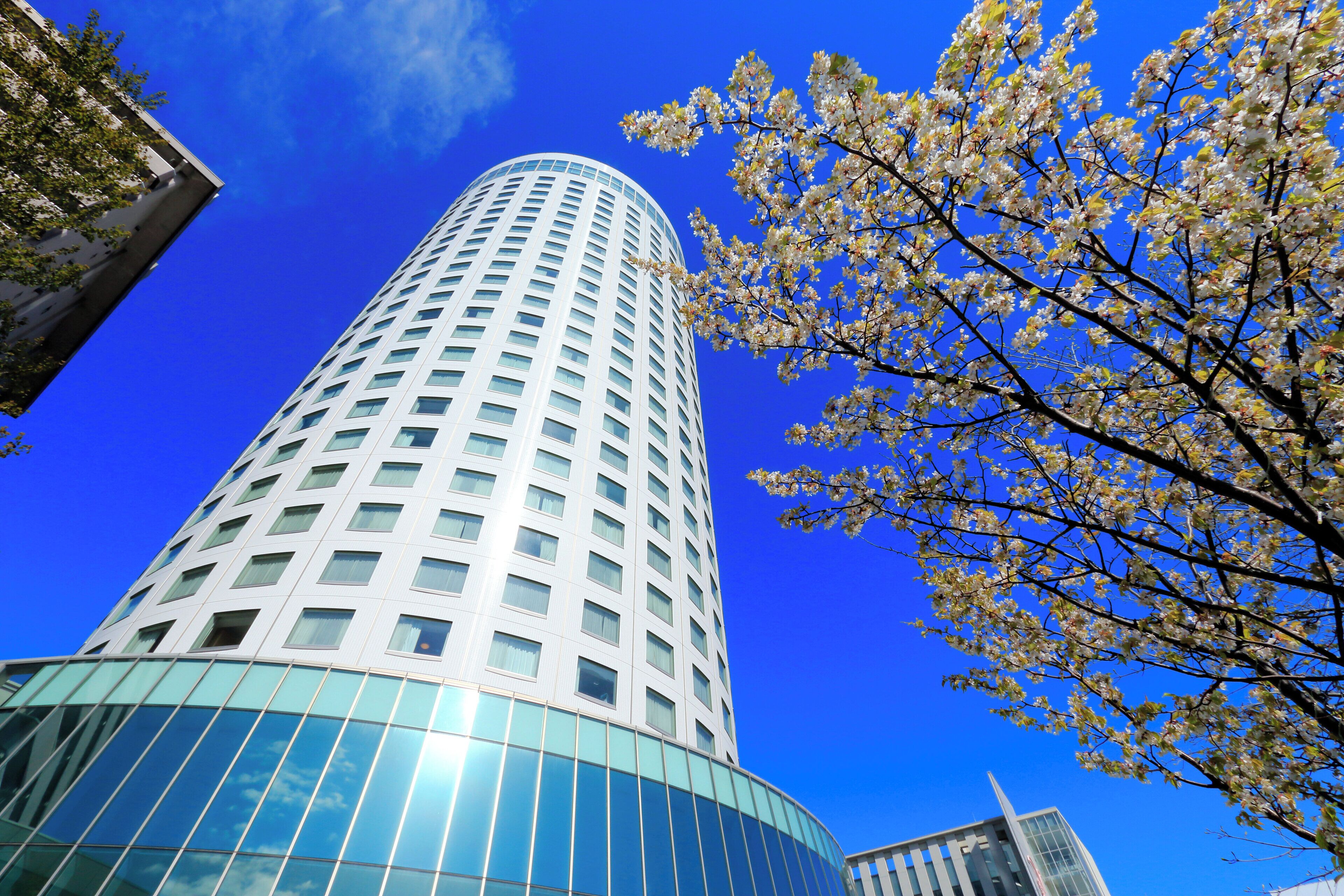 A modern high-rise building with a curved glass facade and a clear blue sky in the background.
