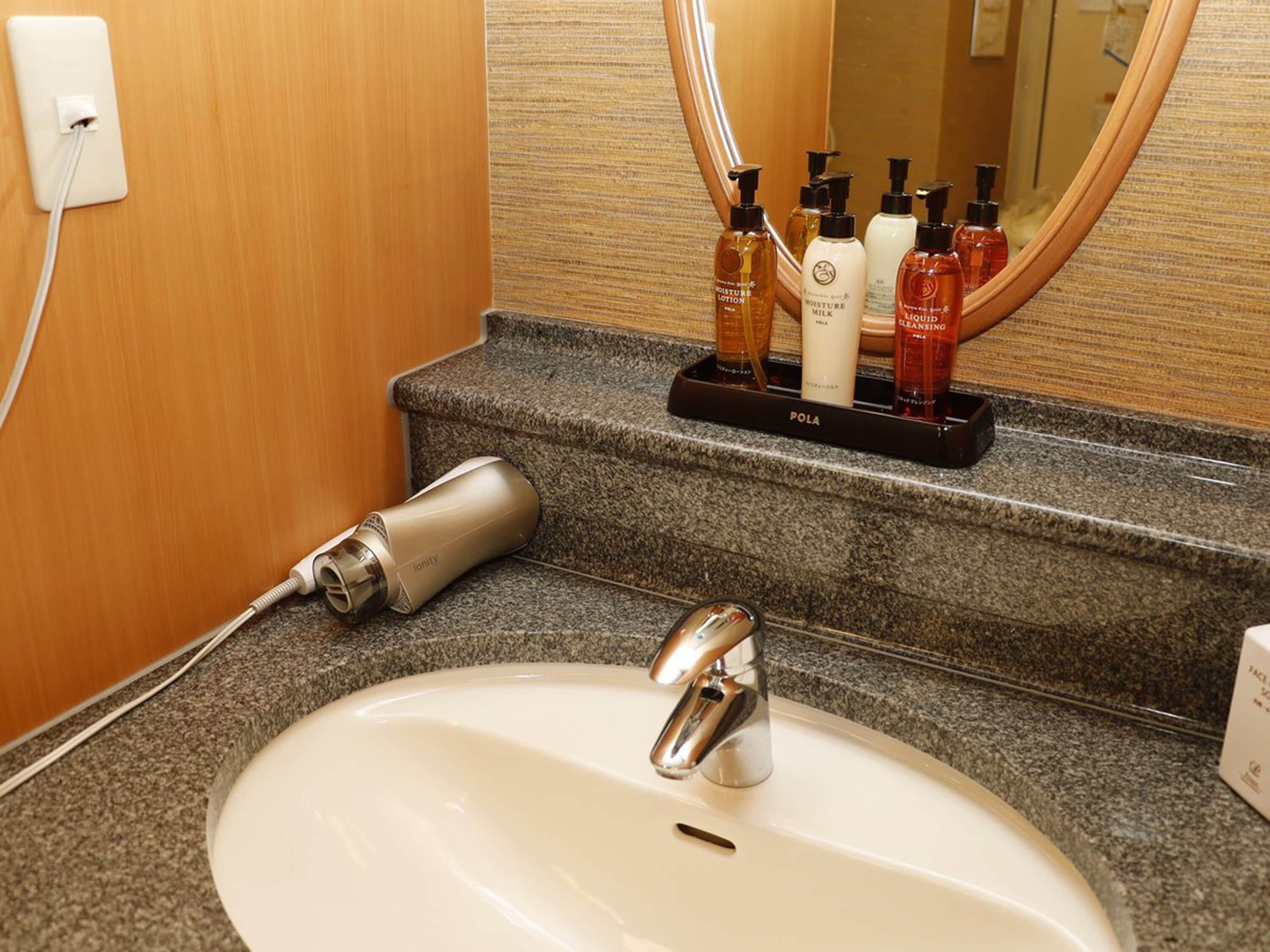 A bathroom with a white sink, a mirror, and toiletries on a tray.