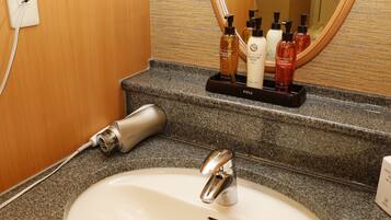 A bathroom with a white sink, a mirror, and toiletries on a tray.