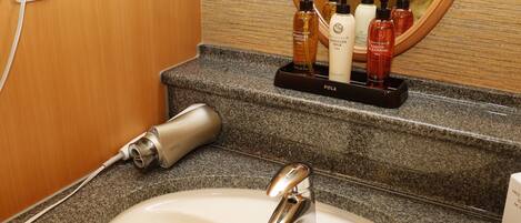 A bathroom with a white sink, a mirror, and toiletries on a tray.