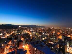 A cityscape at night with illuminated buildings and a clear view of the mountains in the background. - Sapporo Prince Hotel (Sapporo)
