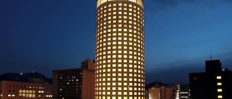 Un hotel alto de diseño circular, con ventanas iluminadas y un letrero en la parte superior.