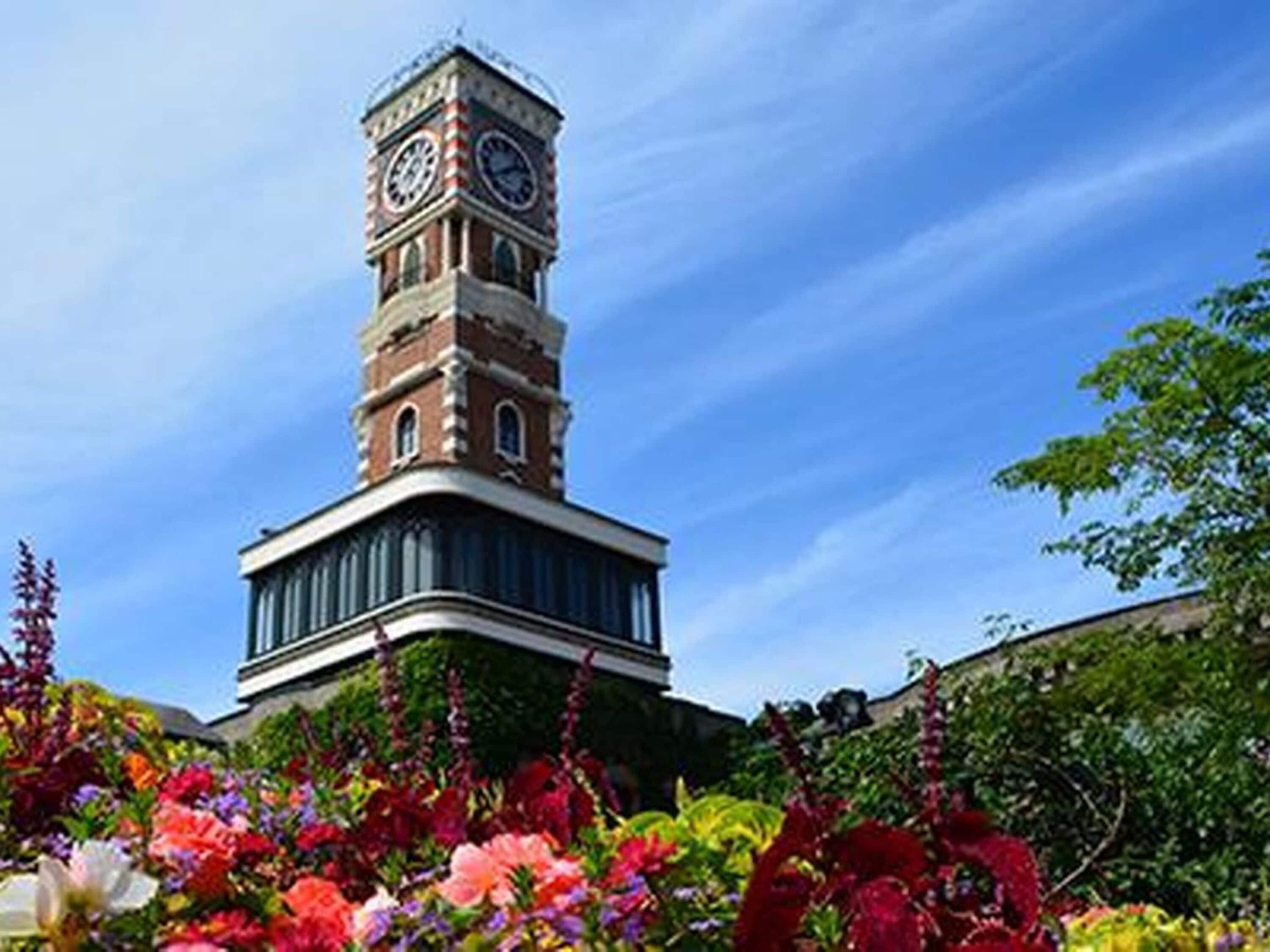 A clock tower with a garden in front.