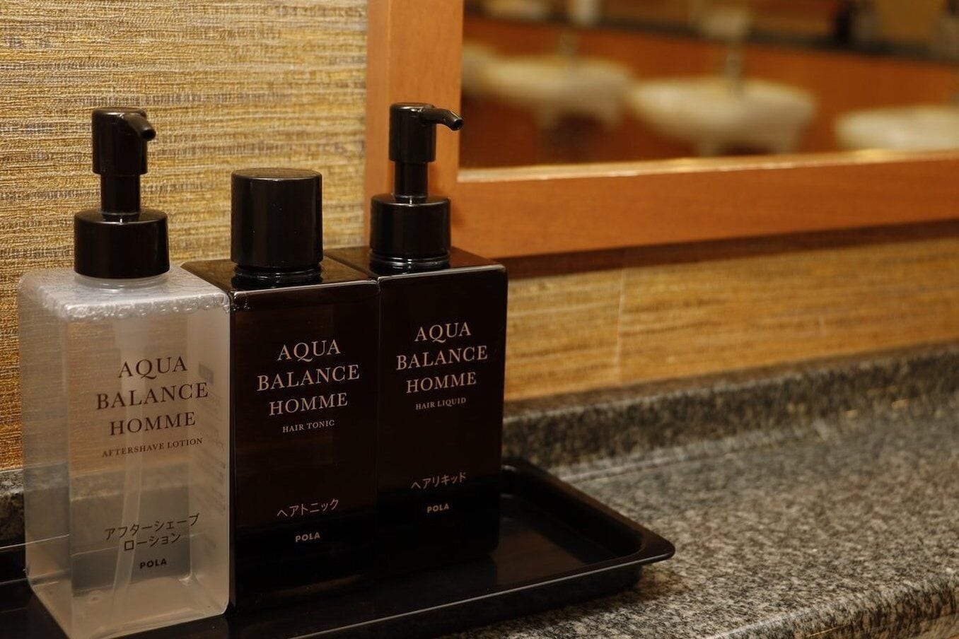 Three bottles of Aqua Balance Homme hair products on a tray in a bathroom.