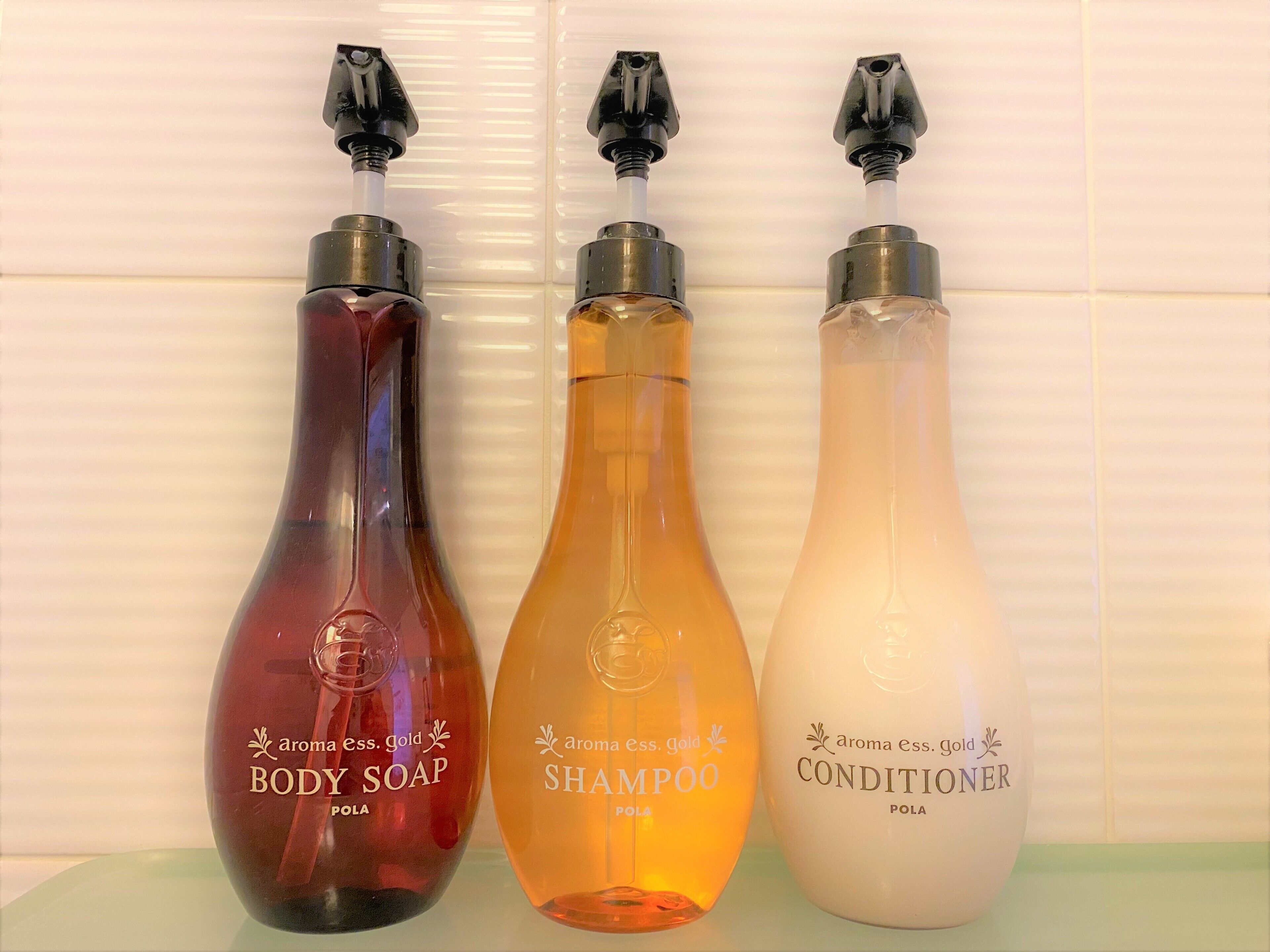 Tres botellas de jabón corporal, champú y acondicionador sobre una estantería.