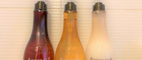 Tres botellas de jabón corporal, champú y acondicionador sobre una estantería.