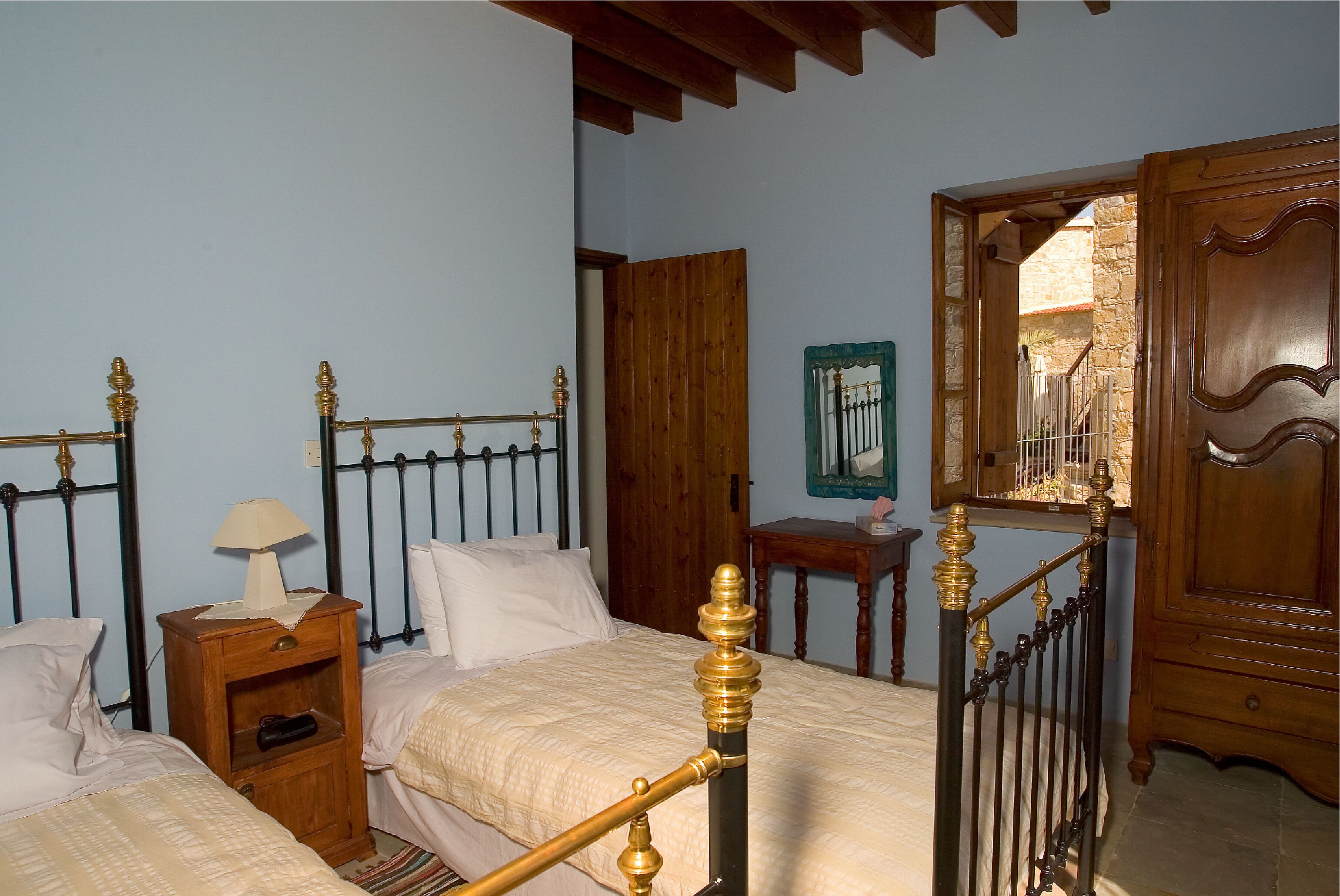 Une chambre à coucher avec un lit en bois, une table de chevet avec une lampe, une armoire en bois et un miroir.