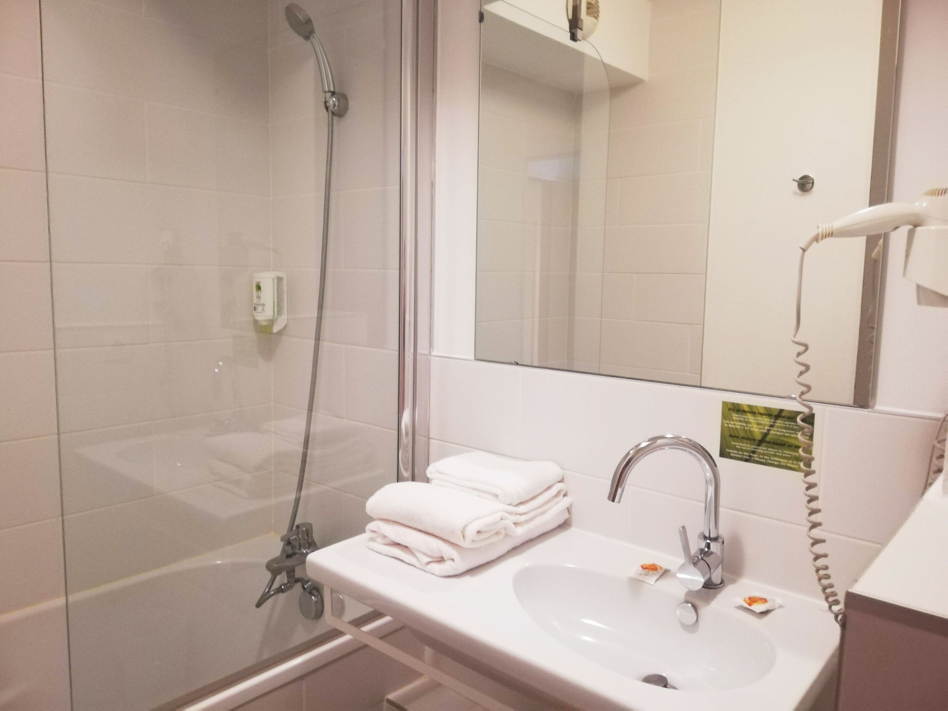 A modern bathroom with a glass-enclosed shower, a white sink, and a mirror.