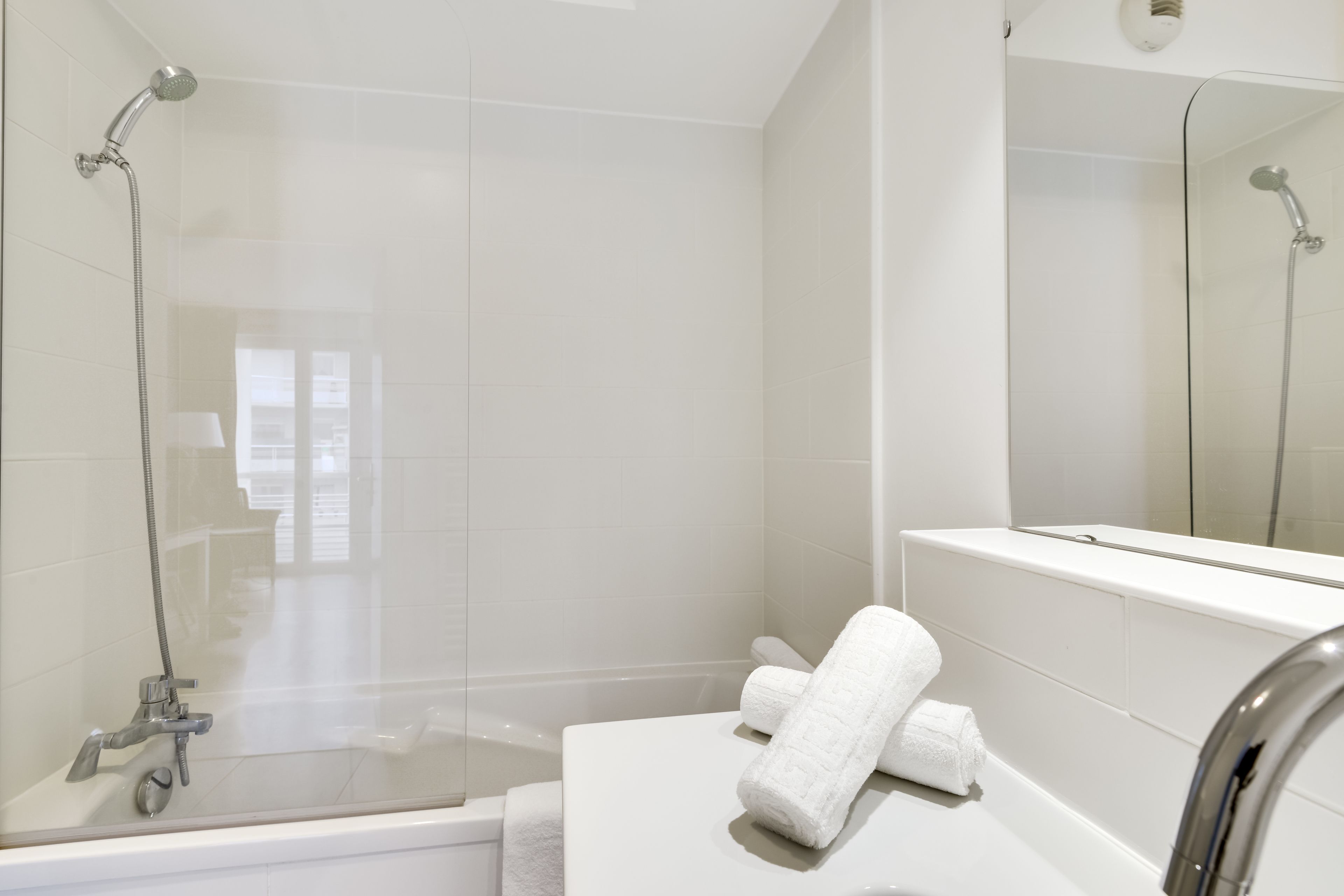 Un baño moderno con ducha de vidrio, una bañera blanca y un espejo grande.