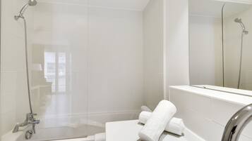 Un baño moderno con ducha de vidrio, una bañera blanca y un espejo grande.