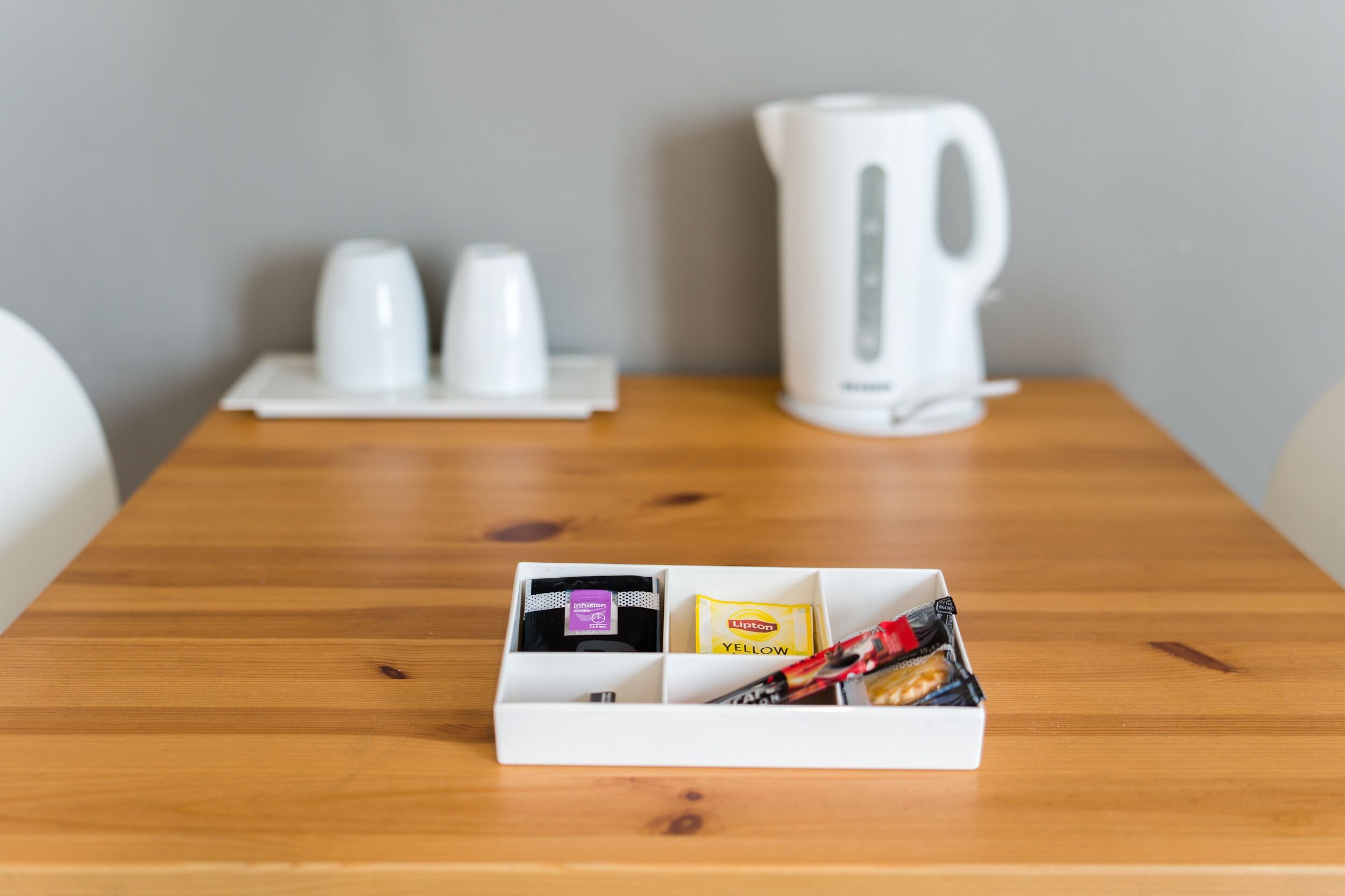 A wooden table with a white box containing Lipton tea and snacks.