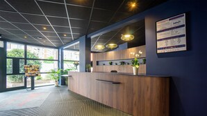 A reception area with a wooden counter, a menu board, and potted plants.