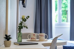 A hotel room with a bed, a small table with two mugs, a book, and a potted plant. - City Residence Strasbourg Centre (Strasbourg)