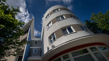 Stunning building with a curved facade and balconies, set amidst lush green surroundings.