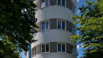 Um edifício de vários andares com fachada curva, grandes janelas e telhado plano.
