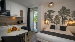 A modern bedroom with a bed, a dining table with breakfast, and a kitchen area. - Lagrange Apart'HOTEL Mulhouse (Mulhouse)